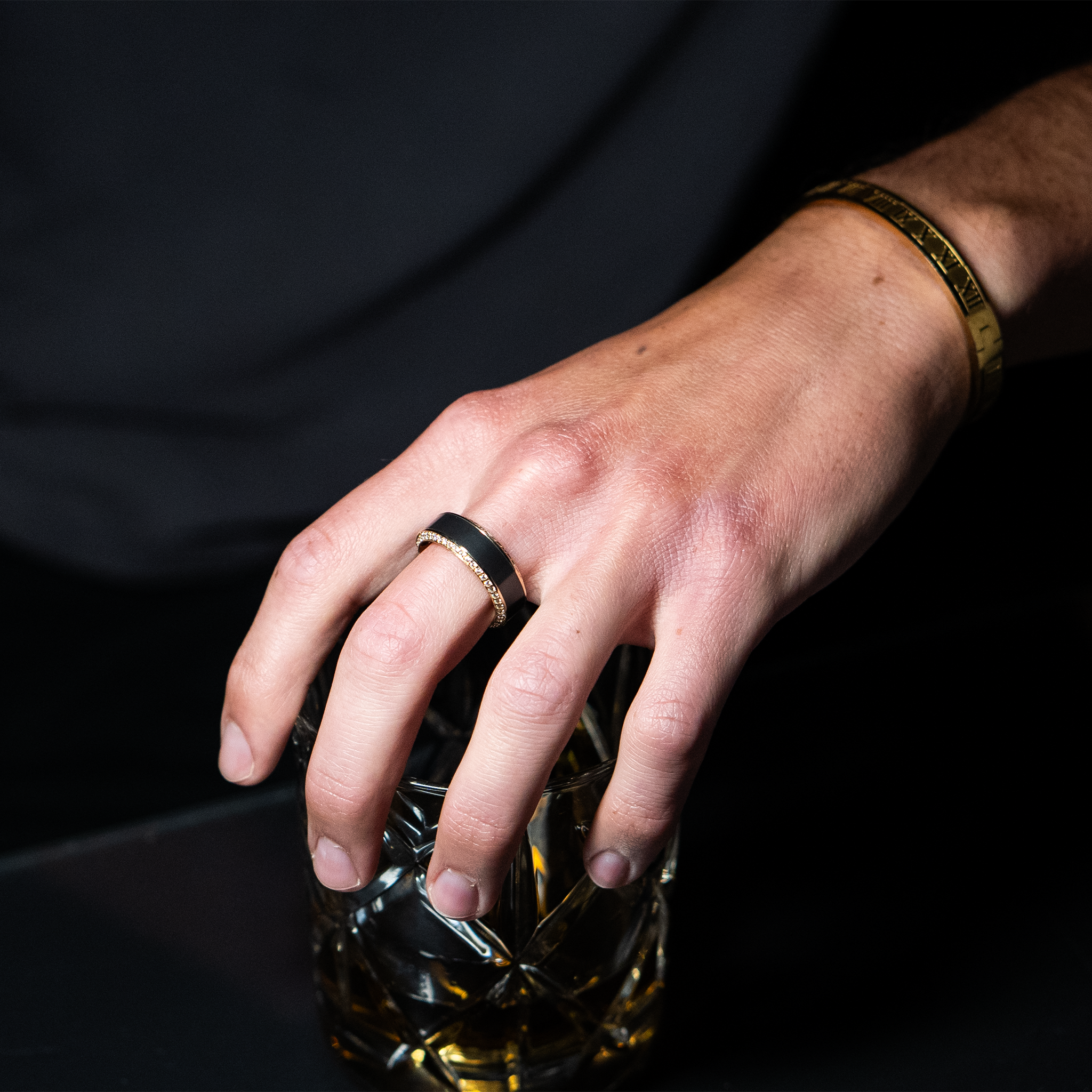 HELIOS ring – 8mm black diamond men’s ring with a yellow gold band, black diamond inlay, and white diamond insets. Worn on hand to showcase fit, contrast, and brilliance in natural lighting.