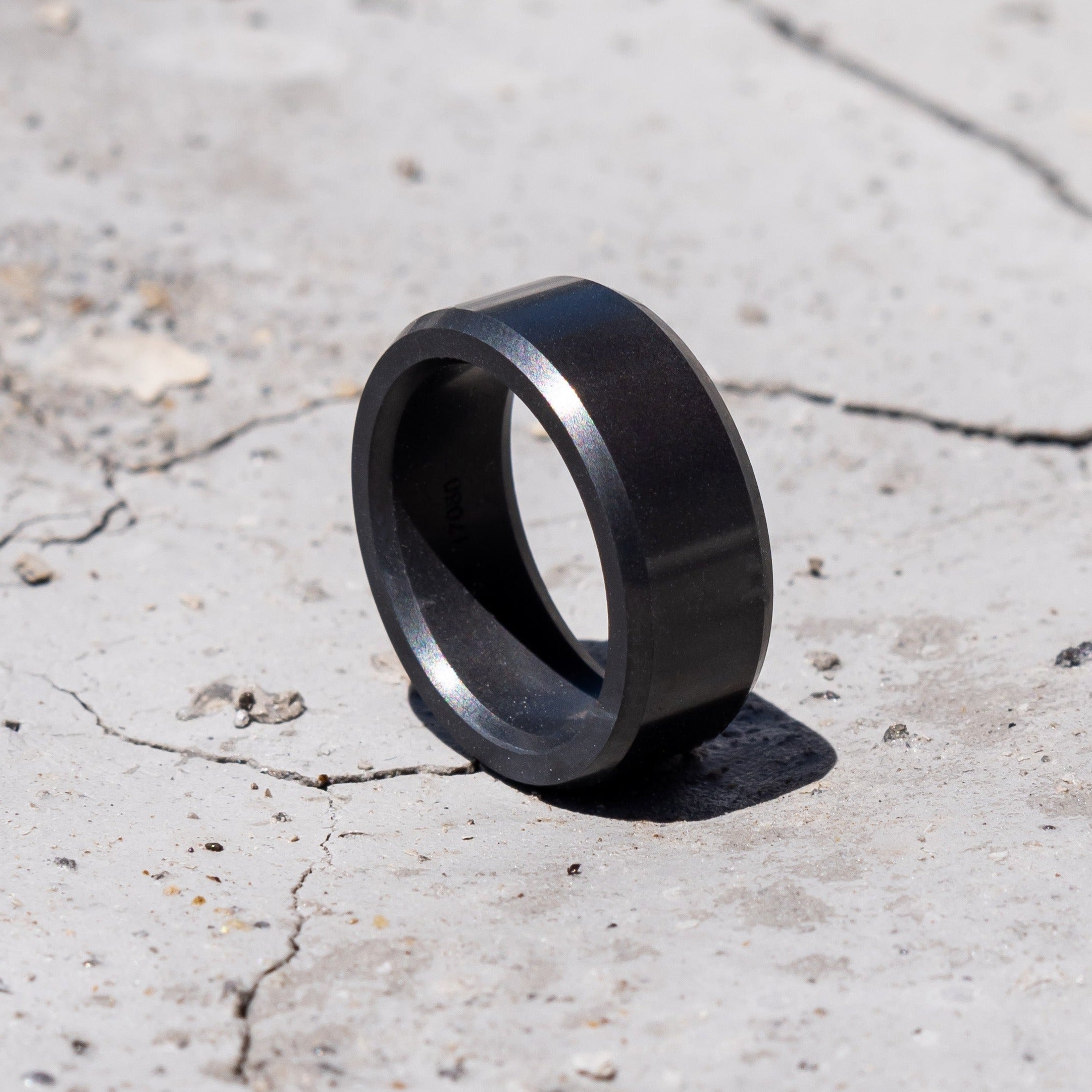Ring shot #1 of men's hands wearing our Elysium ARES solid black diamond ring resting on a marble surface | Men’s Black Diamond Rings | Black Wedding Bands