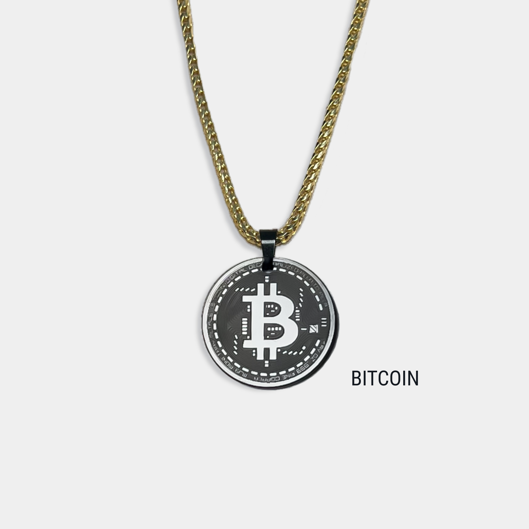Photo of round solid black diamond pendant with bitcoin symbol engraved, attached to gold chain
