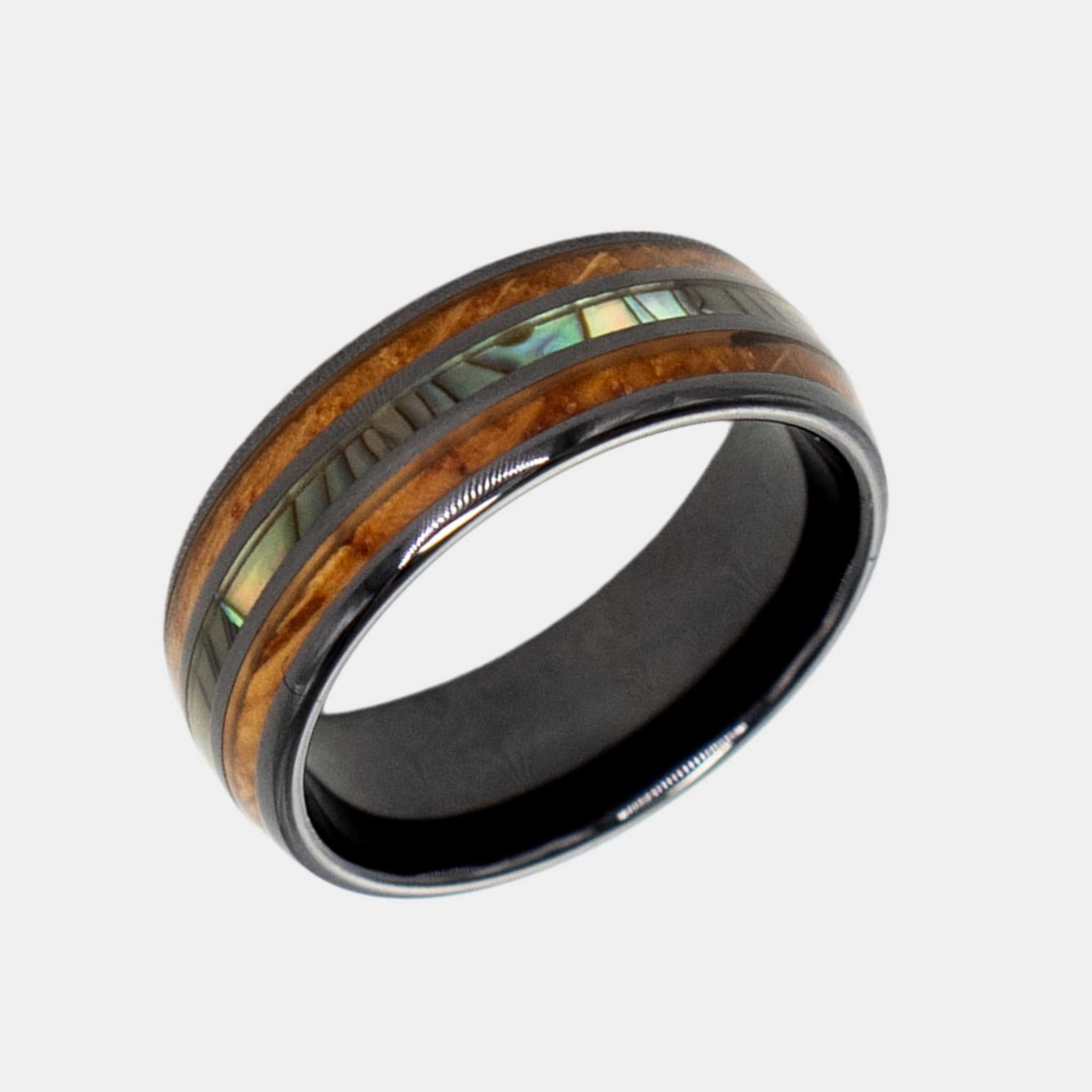 Odysseus ring – Polished Black Ceramic, Featuring a Double Whiskey Barrel Wood Inlay and Abalone Shell Inlay from the Hustler Collection.  Angled view highlighting shape and finish.