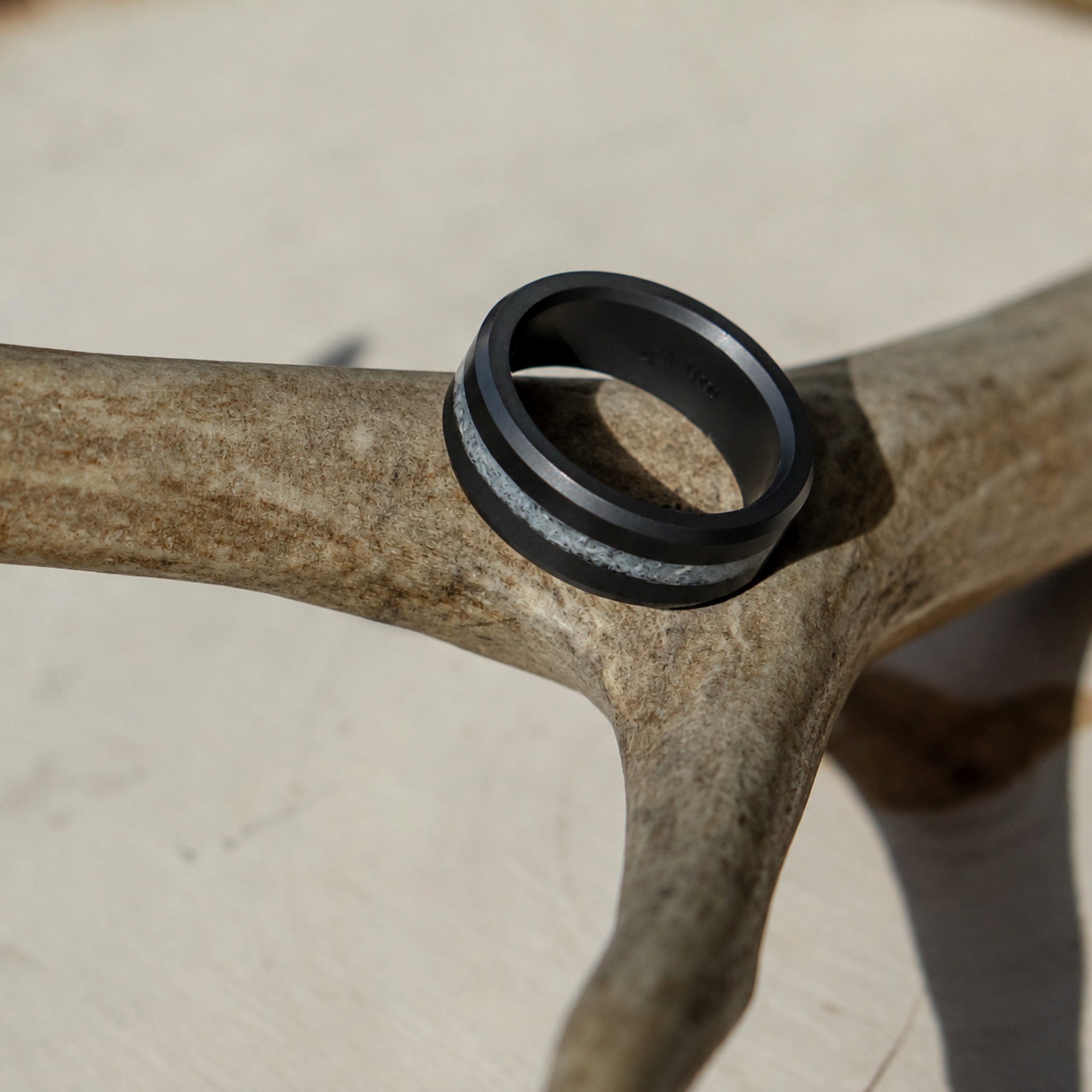 ARES antler inlay wedding band in solid black diamond resting on natural antler